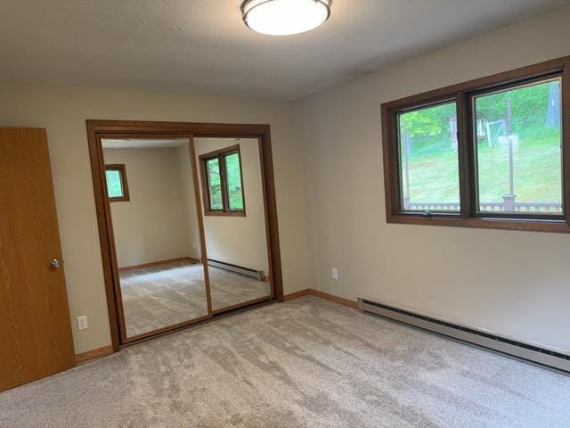 240 12th Ave, Grand Rapids, MN 55744 - unfurnished bedroom featuring baseboard heating, light colored carpet, and a closet