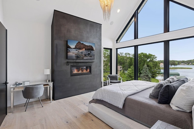 1300 Wildhurst Trl, Orono, MN 55364 - bedroom with a large fireplace, a water view, light wood-type flooring, and lofted ceiling