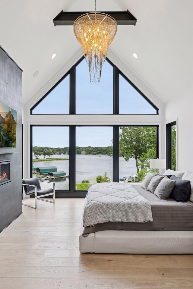 1300 Wildhurst Trl, Orono, MN 55364 - bedroom with a chandelier, multiple windows, a water view, high vaulted ceiling, and a fireplace
