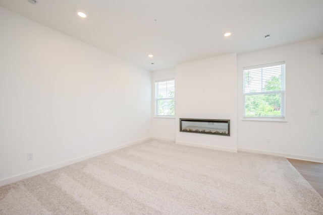 6266 205th St N, Forest Lake, MN 55025 - unfurnished living room with a glass covered fireplace, recessed lighting, and carpet floors