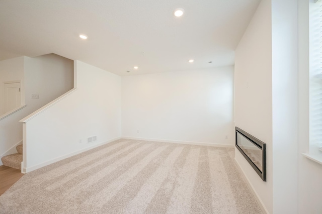 6266 205th St N, Forest Lake, MN 55025 - unfurnished living room featuring recessed lighting, a glass covered fireplace, stairway, heating unit, and light carpet