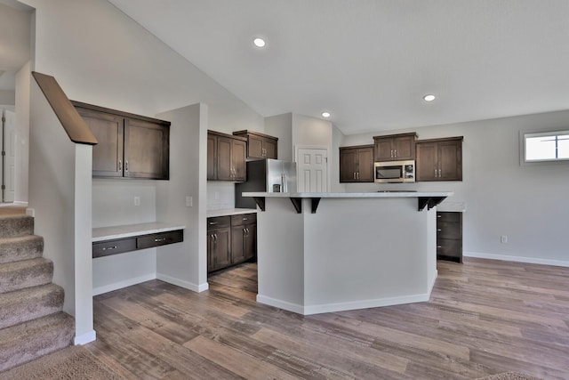 9854 187th Ln NW, Elk River, MN 55330 - kitchen with appliances with stainless steel finishes, dark brown cabinets, light countertops, a breakfast bar, and wood finished floors