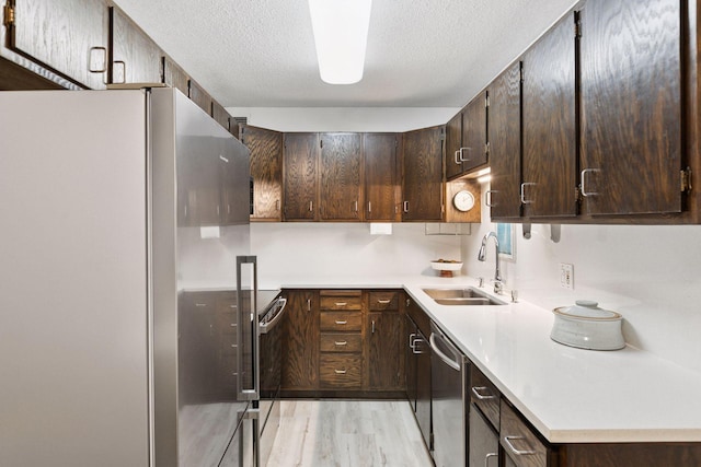 1200 Nicollet Mall Unit 409, Minneapolis, MN 55403 - kitchen featuring appliances with stainless steel finishes, dark brown cabinets, light countertops, light wood finished floors, and a textured ceiling
