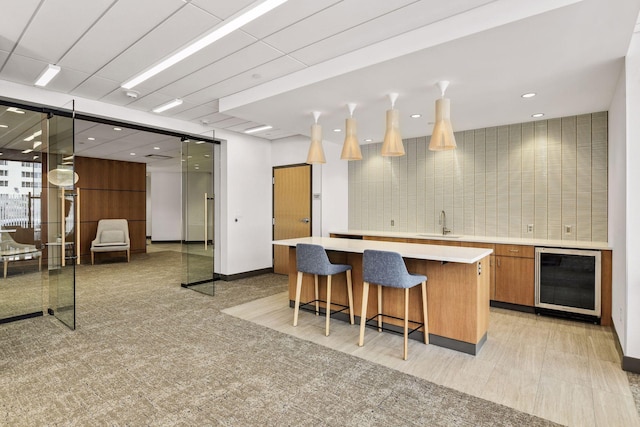 1200 Nicollet Mall Unit 409, Minneapolis, MN 55403 - kitchen with wine cooler, brown cabinets, a center island, light countertops, and a breakfast bar area