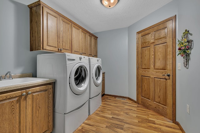 662 Cottonwood Ave, Litchfield, MN 55355 - laundry room featuring washing machine and dryer, cabinet space, light wood-style floors, and a textured ceiling