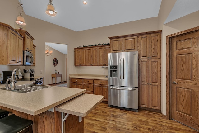 662 Cottonwood Ave, Litchfield, MN 55355 - kitchen with stainless steel appliances, a peninsula, light wood finished floors, brown cabinetry, and a breakfast bar area