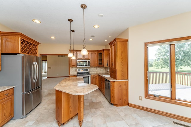 1608 Greystone Ln SW, Rochester, MN 55902 - kitchen with stainless steel appliances, brown cabinetry, a center island, backsplash, and light stone counters