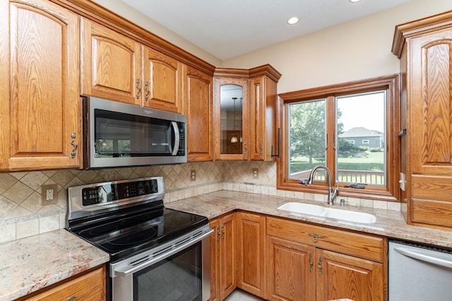 1608 Greystone Ln SW, Rochester, MN 55902 - kitchen with appliances with stainless steel finishes, light stone counters, glass insert cabinets, brown cabinetry, and recessed lighting