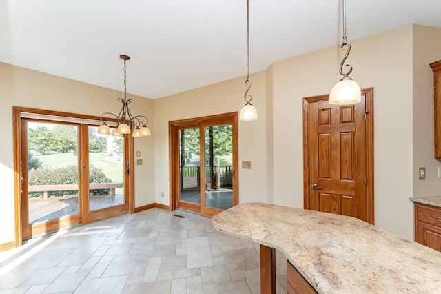 1608 Greystone Ln SW, Rochester, MN 55902 - kitchen featuring stone finish flooring, hanging light fixtures, a chandelier, light stone countertops, and brown cabinetry