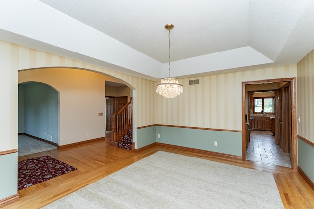 1608 Greystone Ln SW, Rochester, MN 55902 - unfurnished room featuring wood finished floors, arched walkways, wallpapered walls, a chandelier, and stairway
