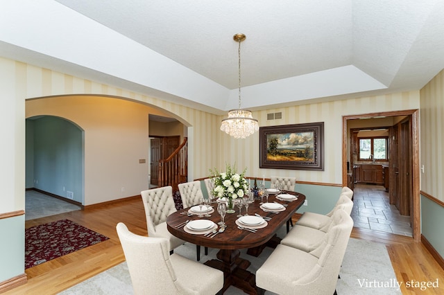 1608 Greystone Ln SW, Rochester, MN 55902 - dining room with arched walkways, a tray ceiling, wallpapered walls, a chandelier, and a textured ceiling