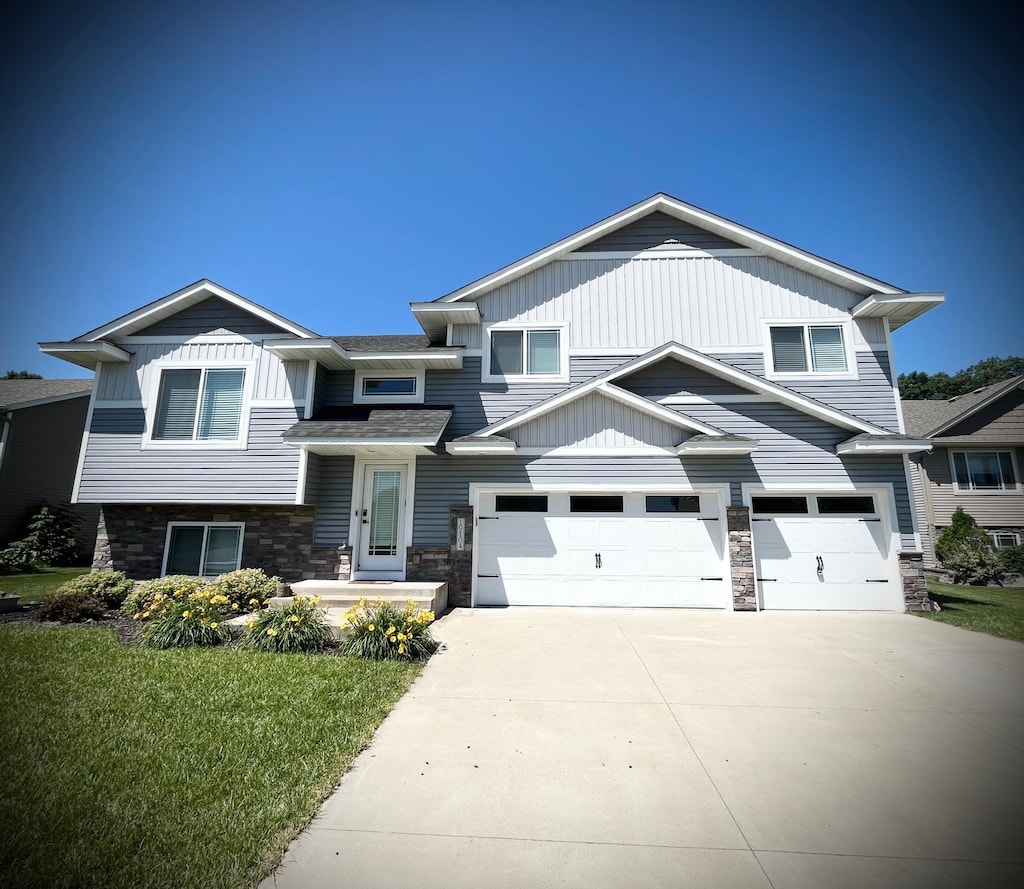 19104 Johnson St NW, Elk River, MN 55330 - view of front of home featuring driveway, an attached garage, stone siding, and a front lawn