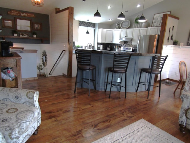1103 15th St, Montevideo, MN 56265 - kitchen featuring freestanding refrigerator, white cabinetry, wood finished floors, a kitchen bar, and dark countertops