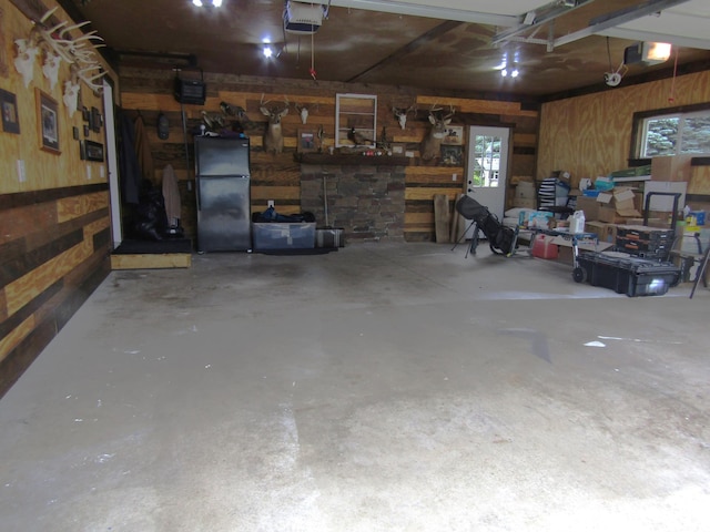 1103 15th St, Montevideo, MN 56265 - garage featuring a garage door opener, wood walls, and freestanding refrigerator