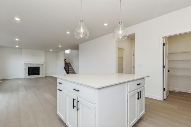 4021 Heath Ln N, Oakdale, MN 55128 - kitchen with light wood finished floors, a center island, recessed lighting, a stone fireplace, and white cabinets