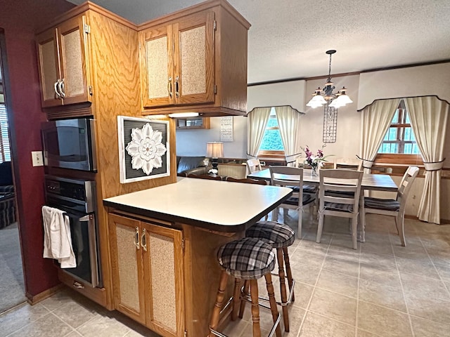 8180 Diane St, Circle Pines, MN 55014 - kitchen with oven, stainless steel microwave, a chandelier, light tile patterned floors, and a peninsula