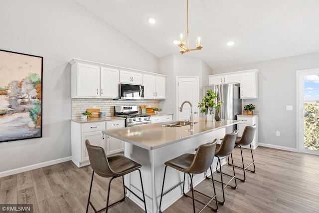 1013 2nd St NW, Delano, MN 55328 - kitchen with appliances with stainless steel finishes, tasteful backsplash, light countertops, light wood-style floors, and a kitchen bar