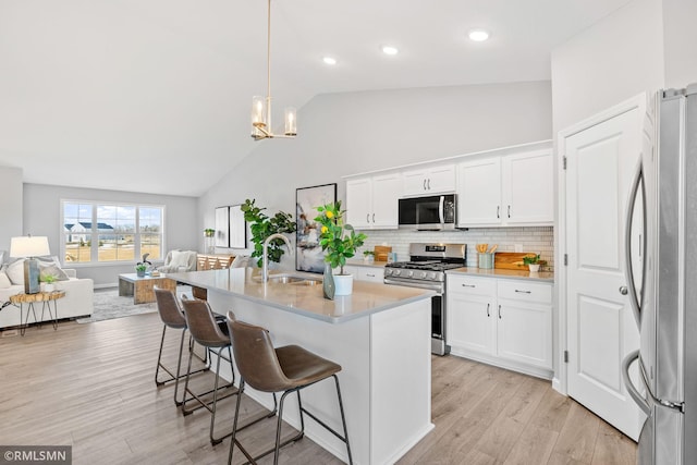 1013 2nd St NW, Delano, MN 55328 - kitchen featuring stainless steel appliances, light countertops, open floor plan, a breakfast bar, and backsplash