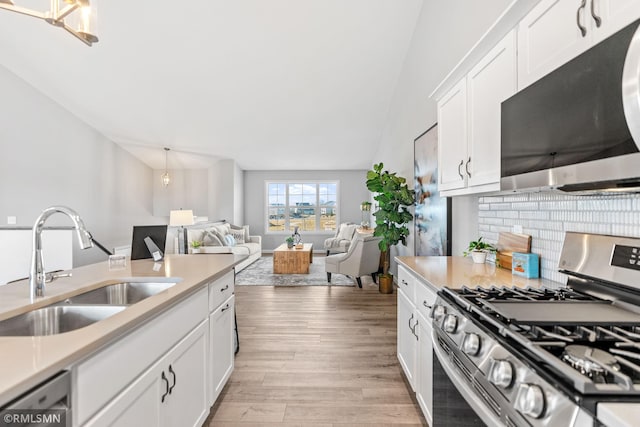 1013 2nd St NW, Delano, MN 55328 - kitchen with appliances with stainless steel finishes, light wood-style floors, backsplash, light countertops, and vaulted ceiling