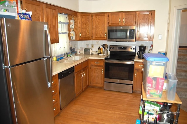 1445 Ottawa Ave S, Golden Valley, MN 55416 - kitchen featuring stainless steel appliances, light countertops, brown cabinetry, light wood finished floors, and backsplash