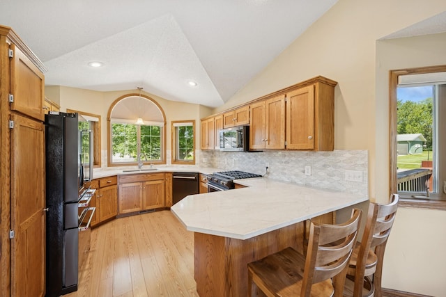 24482 18th Ave, Saint Augusta, MN 56301 - kitchen with appliances with stainless steel finishes, a peninsula, vaulted ceiling, light wood-type flooring, and backsplash
