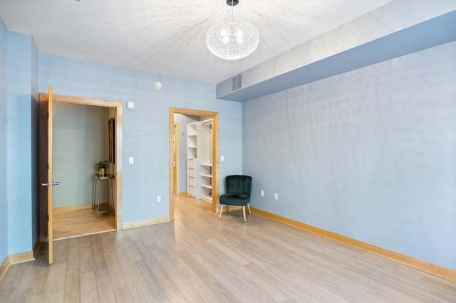 317 Groveland Ave Unit 106, Minneapolis, MN 55403 - unfurnished bedroom featuring a chandelier, wood finished floors, and a spacious closet