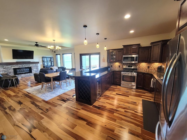 11003 Eagles Nest Ct, Audubon, MN 56511 - kitchen with stainless steel appliances, light wood-style flooring, dark brown cabinets, decorative backsplash, and a fireplace