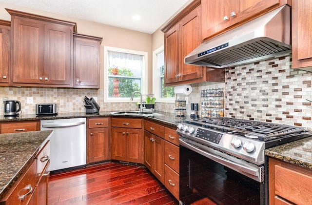 6274 Zircon Ln N, Maple Grove, MN 55311 - kitchen featuring appliances with stainless steel finishes, under cabinet range hood, dark wood-style flooring, dark stone counters, and brown cabinetry
