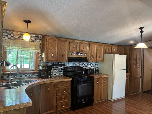 77165 Stepan Rd, Kettle River Twp, MN 55795 - kitchen with black range with gas cooktop, freestanding refrigerator, extractor fan, brown cabinets, and backsplash