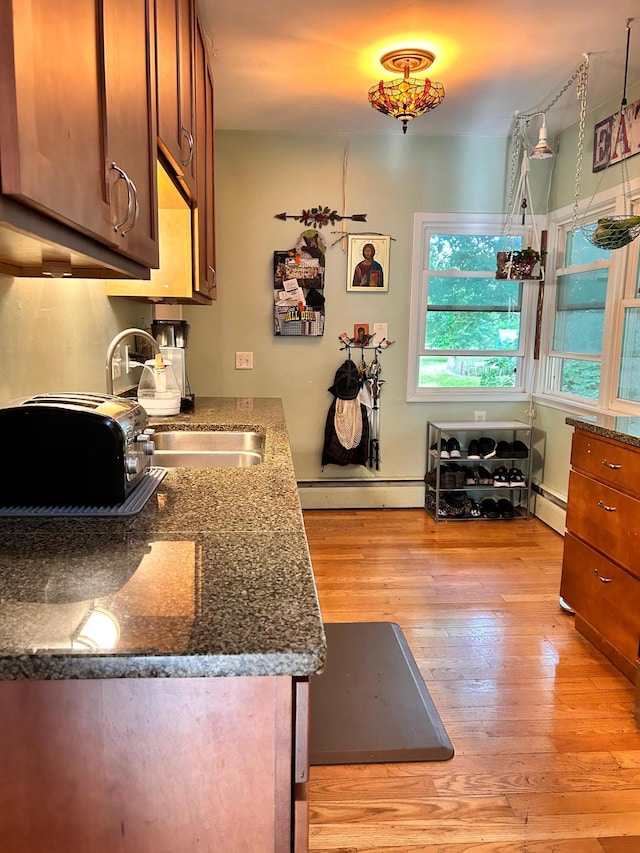 3821 Foss Rd, Saint Anthony, MN 55421 - kitchen with light wood finished floors, a baseboard heating unit, dark stone countertops, and brown cabinets