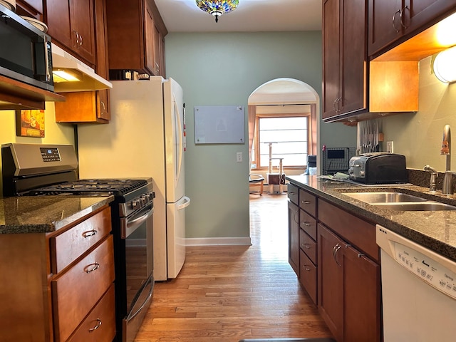 3821 Foss Rd, Saint Anthony, MN 55421 - kitchen featuring stainless steel appliances, under cabinet range hood, light wood finished floors, arched walkways, and dark stone counters