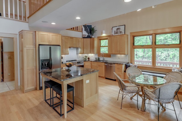 31767 Deacons Way, Pequot Lakes, MN 56472 - kitchen with appliances with stainless steel finishes, light brown cabinets, a high ceiling, dark stone counters, and light wood-type flooring