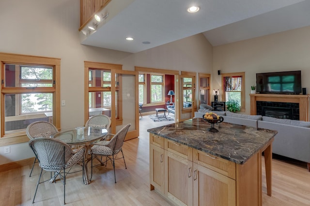 31767 Deacons Way, Pequot Lakes, MN 56472 - kitchen featuring light wood finished floors, high vaulted ceiling, a tile fireplace, open floor plan, and a center island