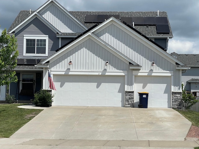 5437 154th St W, Apple Valley, MN 55124 - view of front facade with concrete driveway, roof mounted solar panels, board and batten siding, a garage, and a shingled roof