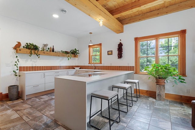 33245 Teal Ave, Shafer Twp, MN 55074 - kitchen featuring white cabinetry, a kitchen bar, a peninsula, a wooden ceiling with exposed beams, and light countertops
