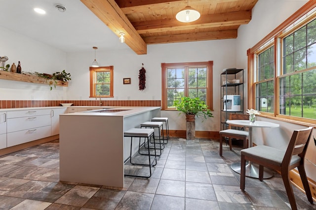 33245 Teal Ave, Shafer Twp, MN 55074 - kitchen with plenty of natural light, white cabinets, a peninsula, a wooden ceiling with exposed beams, and a kitchen bar
