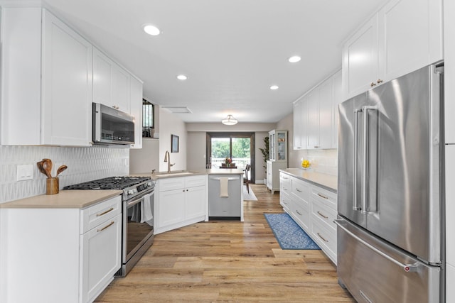 12816 95th Ave N, Maple Grove, MN 55369 - kitchen with appliances with stainless steel finishes, a peninsula, light wood-style flooring, recessed lighting, and white cabinetry