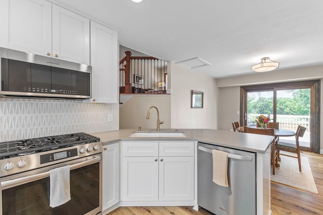 12816 95th Ave N, Maple Grove, MN 55369 - kitchen featuring appliances with stainless steel finishes, a peninsula, light countertops, and light wood-style floors
