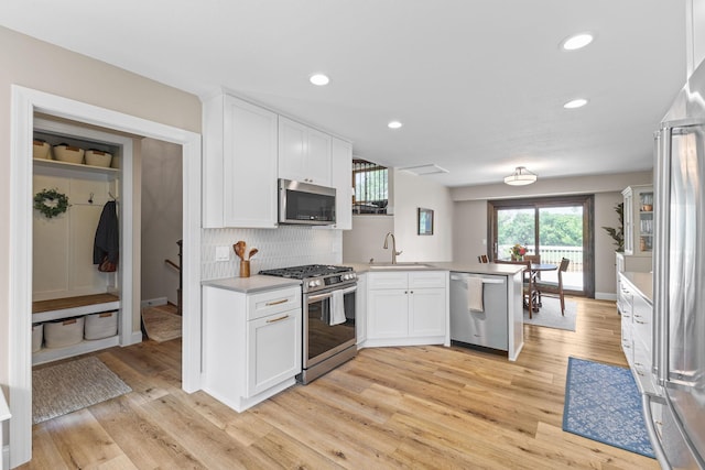12816 95th Ave N, Maple Grove, MN 55369 - kitchen with appliances with stainless steel finishes, a peninsula, white cabinets, light wood-style floors, and recessed lighting