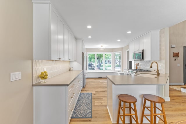 12816 95th Ave N, Maple Grove, MN 55369 - kitchen featuring appliances with stainless steel finishes, light wood-style floors, recessed lighting, decorative backsplash, and a peninsula