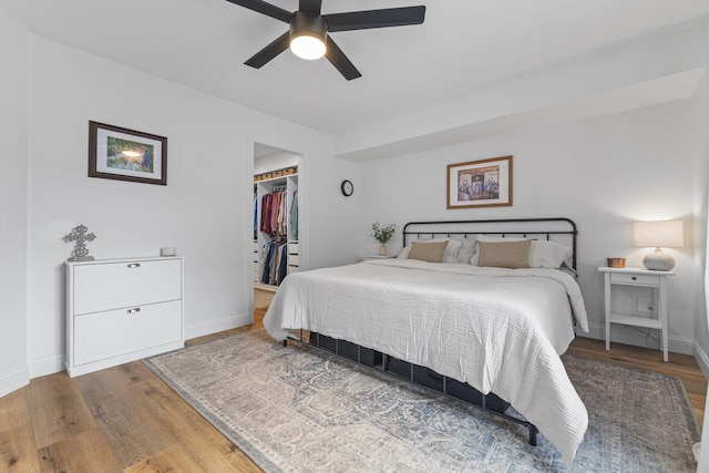 12816 95th Ave N, Maple Grove, MN 55369 - bedroom featuring wood finished floors, a walk in closet, a closet, and ceiling fan