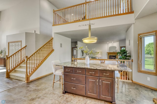 4375 58th St S, Fargo, ND 58104 - kitchen featuring a high ceiling, a kitchen breakfast bar, a fireplace, light stone counters, and hanging light fixtures