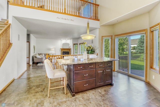 4375 58th St S, Fargo, ND 58104 - kitchen with a fireplace, dark brown cabinets, light stone counters, open floor plan, and a high ceiling