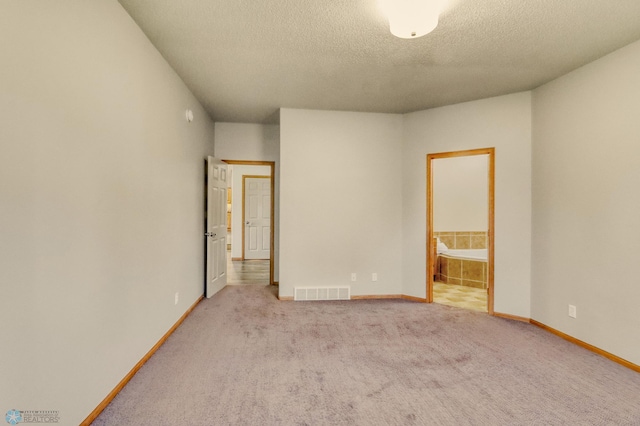 4375 58th St S, Fargo, ND 58104 - unfurnished bedroom featuring a textured ceiling, carpet flooring, and connected bathroom