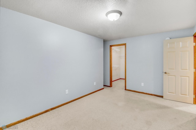 4375 58th St S, Fargo, ND 58104 - unfurnished bedroom with a textured ceiling, light colored carpet, a walk in closet, and a closet