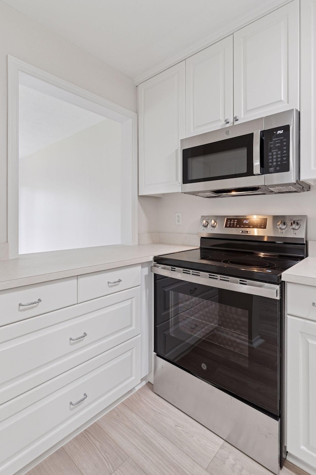 4100 Parklawn Ave Unit 118, Edina, MN 55435 - kitchen with appliances with stainless steel finishes, white cabinets, light countertops, and light wood-style flooring