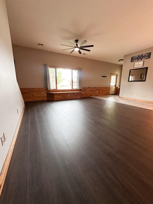 405 Fir Ave, Frazee, MN 56544 - unfurnished living room with wainscoting, ceiling fan, healthy amount of natural light, dark wood-style floors, and a textured ceiling