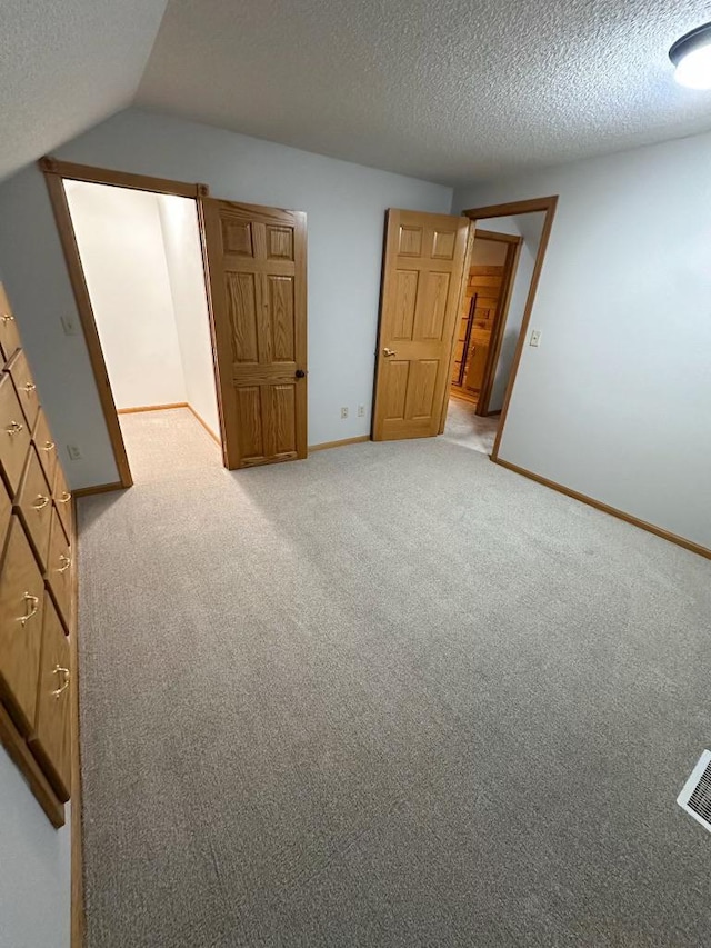 405 Fir Ave, Frazee, MN 56544 - unfurnished bedroom with a textured ceiling, light colored carpet, and vaulted ceiling