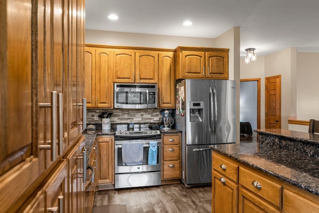 26943 140th St NW, Zimmerman, MN 55398 - kitchen with stainless steel appliances, brown cabinetry, tasteful backsplash, dark wood-type flooring, and dark stone counters