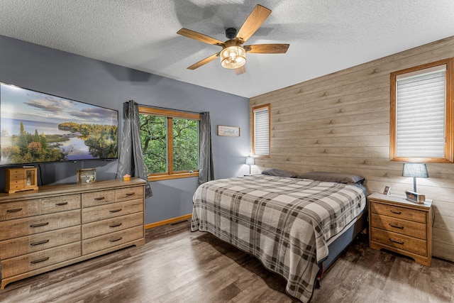 26943 140th St NW, Zimmerman, MN 55398 - bedroom with wood walls, a textured ceiling, wood finished floors, and a ceiling fan